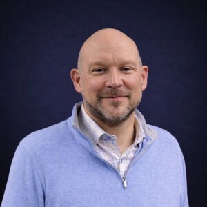 Man smiling in a blue sweater.